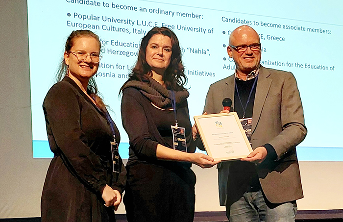 two women and a man holding a certificate