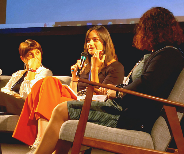 Three women sitting, one talking in microphone in the middle