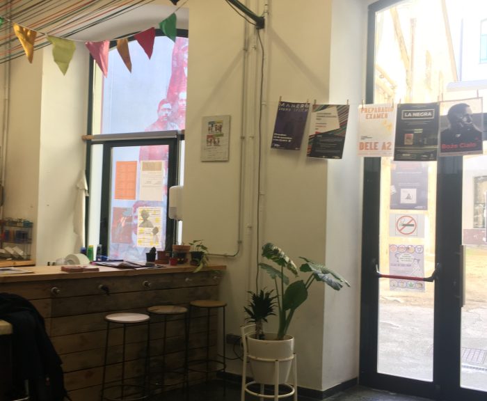 Picture of the entrance to Association DOTA, with posters, a coffee bar counter and a plant