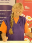 A smiling elderly woman standing behind a desk