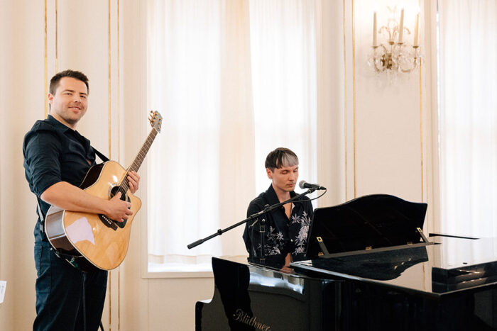 two men, one playing a quitar, and one playing a piano