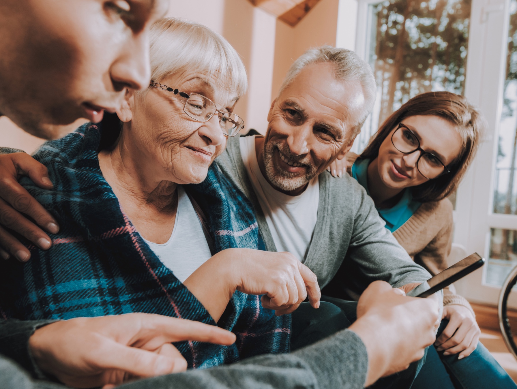 Younger familiy members helping an older woman using a smartphone