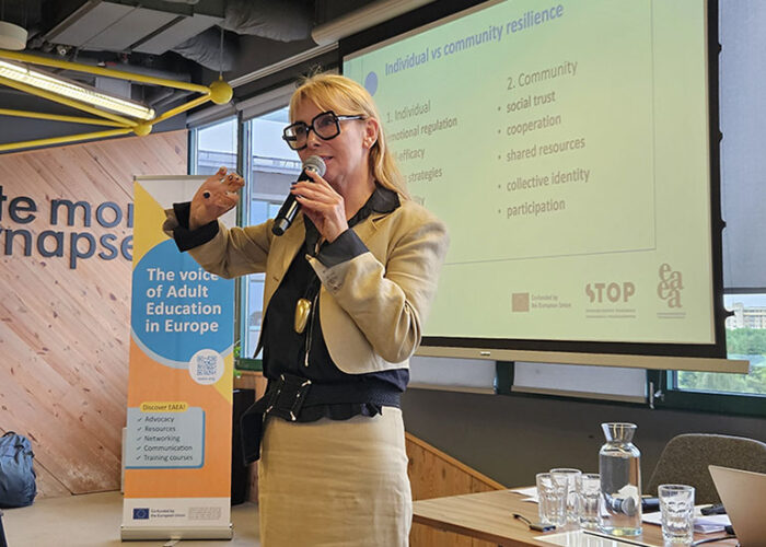 a woman standing in front of a conference room, presentation in the background